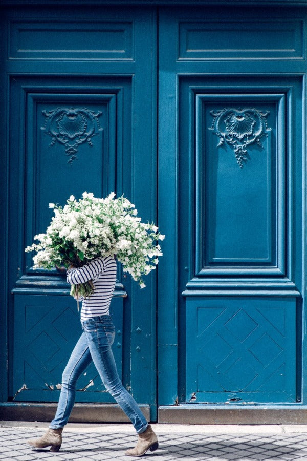 Fiercely Feminine is a photo of a girl in Paris in St Germain des Prés with a romantic bouquet of lilacs and is part of a limited edition series named Young Girl in Bloom by photographer Carla Coulson celebrating women loving and believing in themselves and building their self esteem by trusting their intuition.